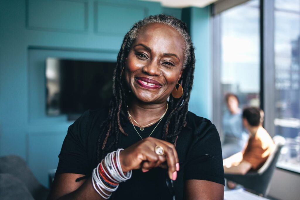 Woman,With,Dreadlocks,Smiling,At,The,Camera,During,A,Meeting