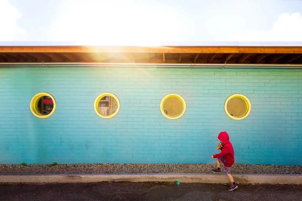 boy in red hoodie walks near blue wall