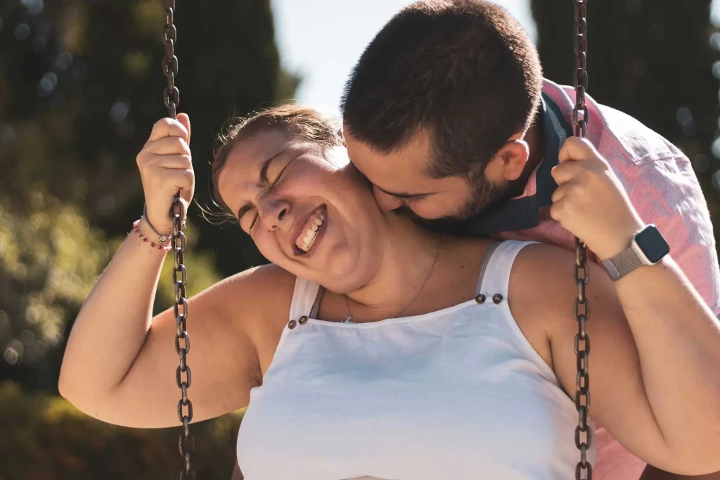 man kisses girlfriend on swing 2034084089