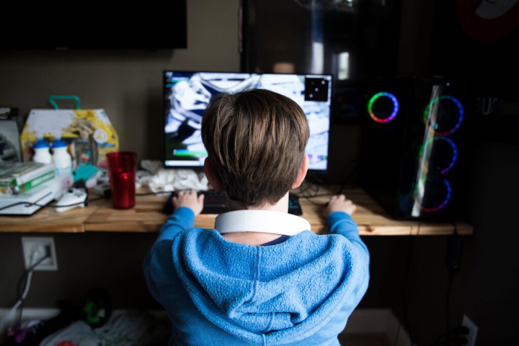 Rear,View,Of,Teen,Boy,Playing,Gaming,Computer,On,A