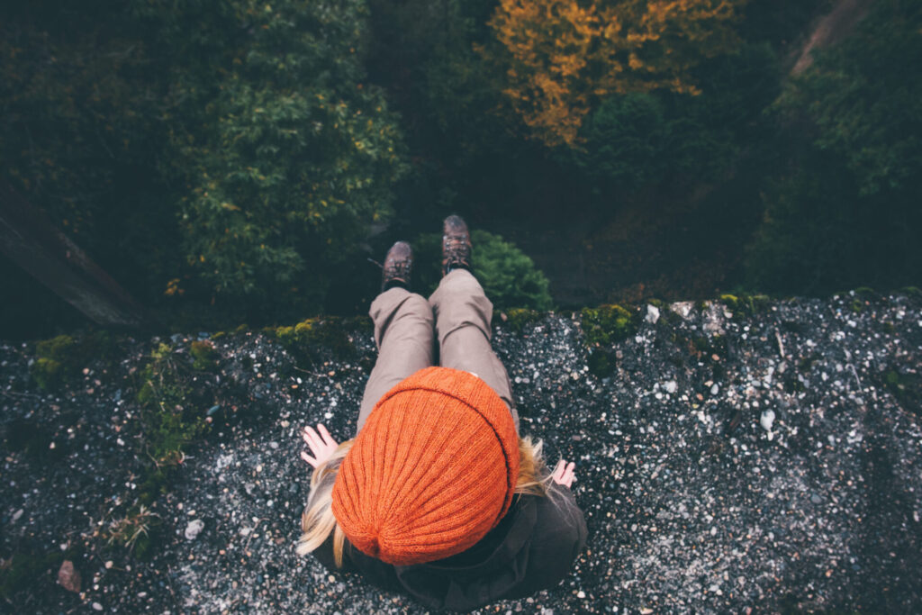 Woman,Traveler,Sitting,On,Cliff,Bridge,With,Forest,Aerial,View