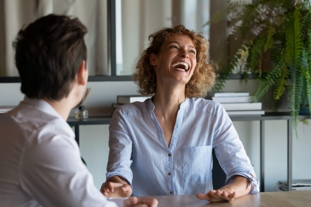 Cheerful,Young,Businesswoman,Laughing,,Enjoying,Pleasant,Conversation,With,Colleague,In