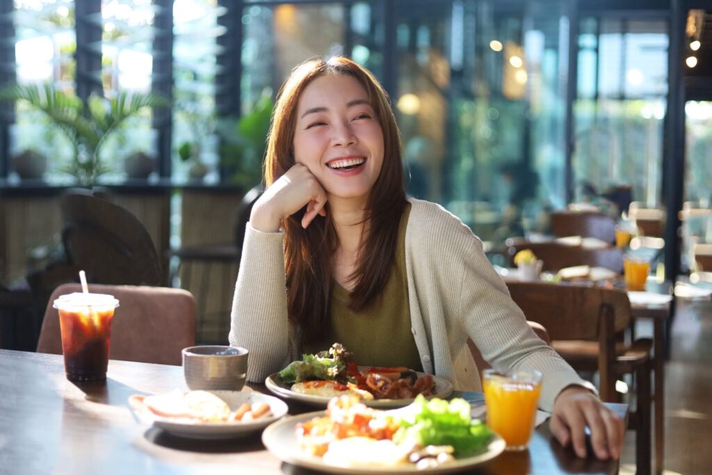 Beautiful,Asian,Woman,Joyful,Eating,A,Meal,In,Restaurant.