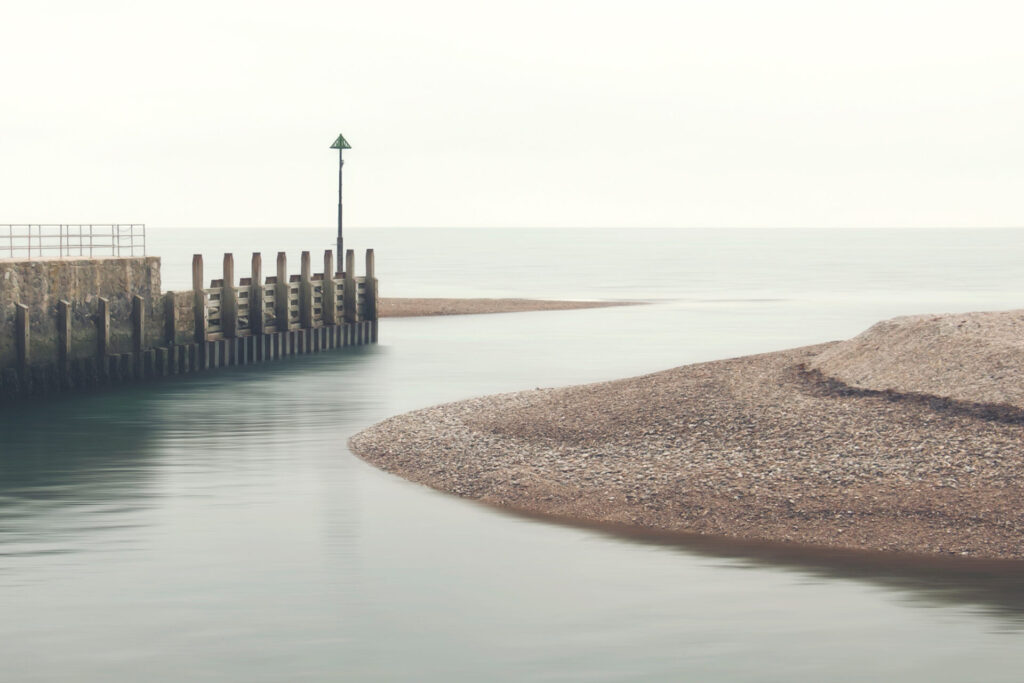 A,Calm,Pebble,Beach,Seascape,Showing,A,River,Flowing,Into